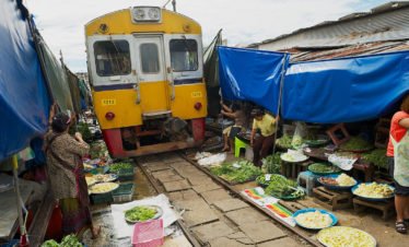 train-passes-by-the-mae-klong-railway-tracks-market-in-samut-songkram-thailand-100119117